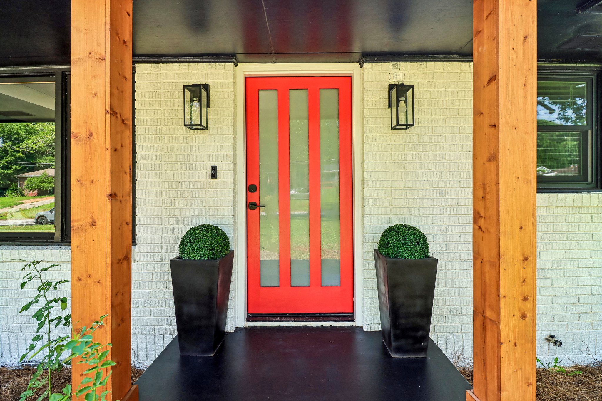 Statement red door framed by warm wood posts and modern sconces