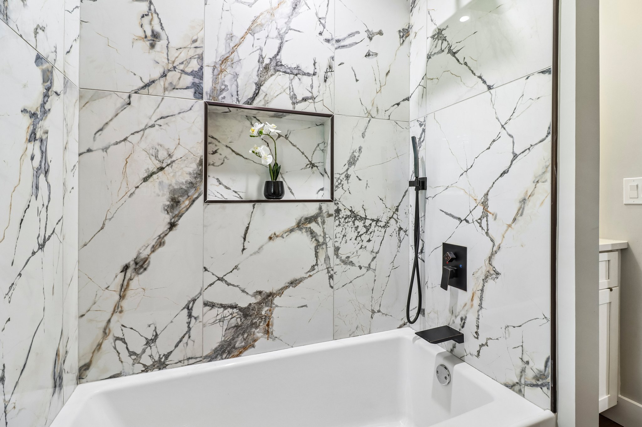 Built-in niche and hand shower complete the custom tub surround