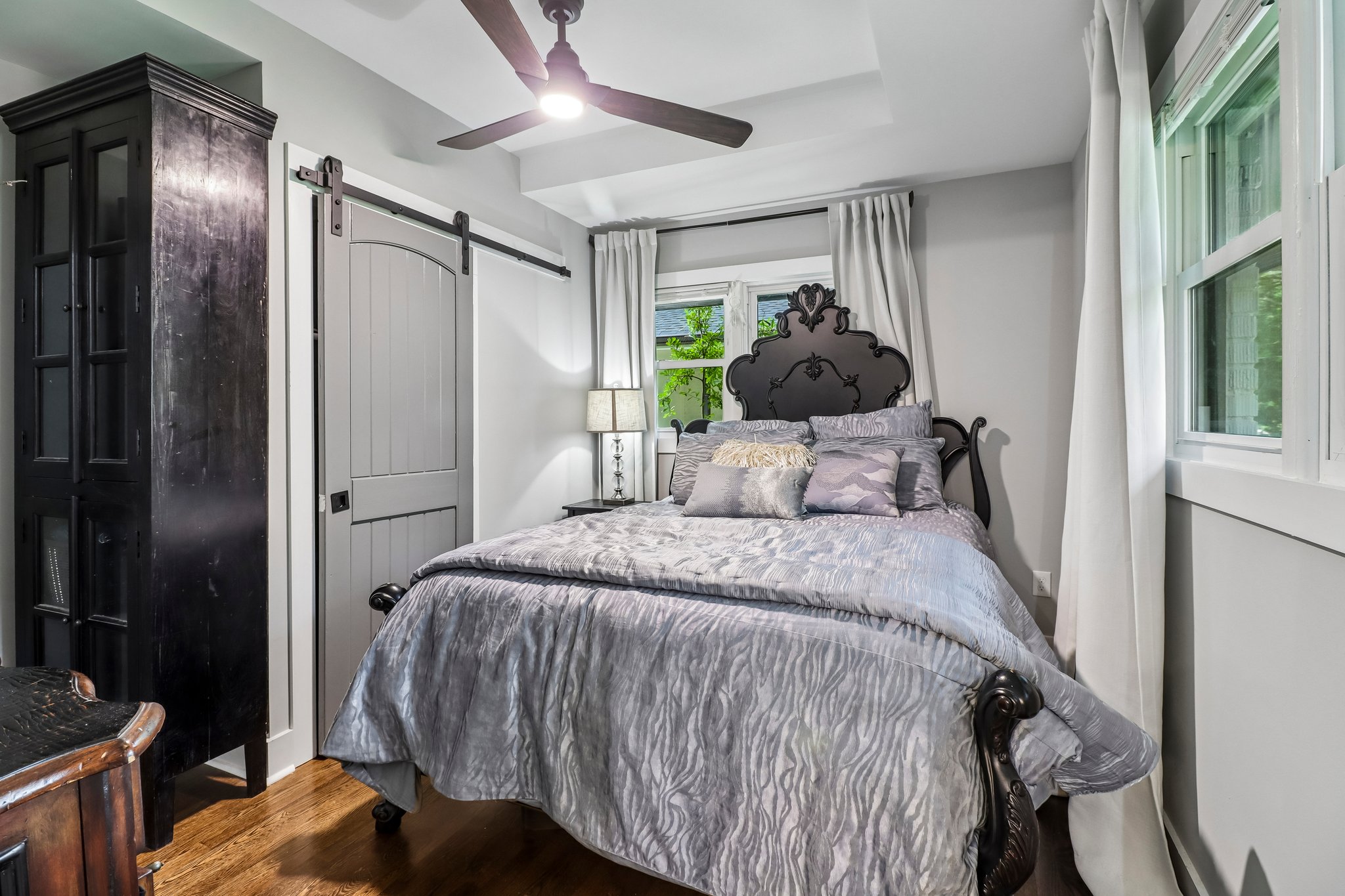 Tray ceiling, ceiling fan and barn-style closet door elevate the retreat