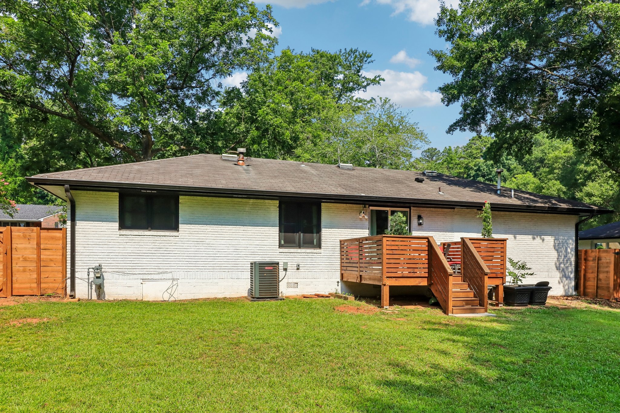 Single-level rear exterior framed by lawn and mature shade trees