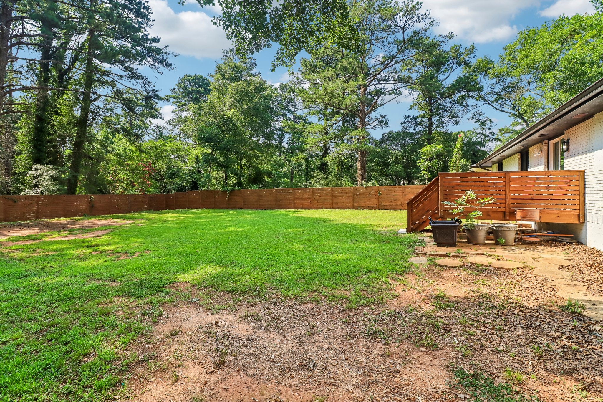 Side perspective captures the deck and wooded backyard setting